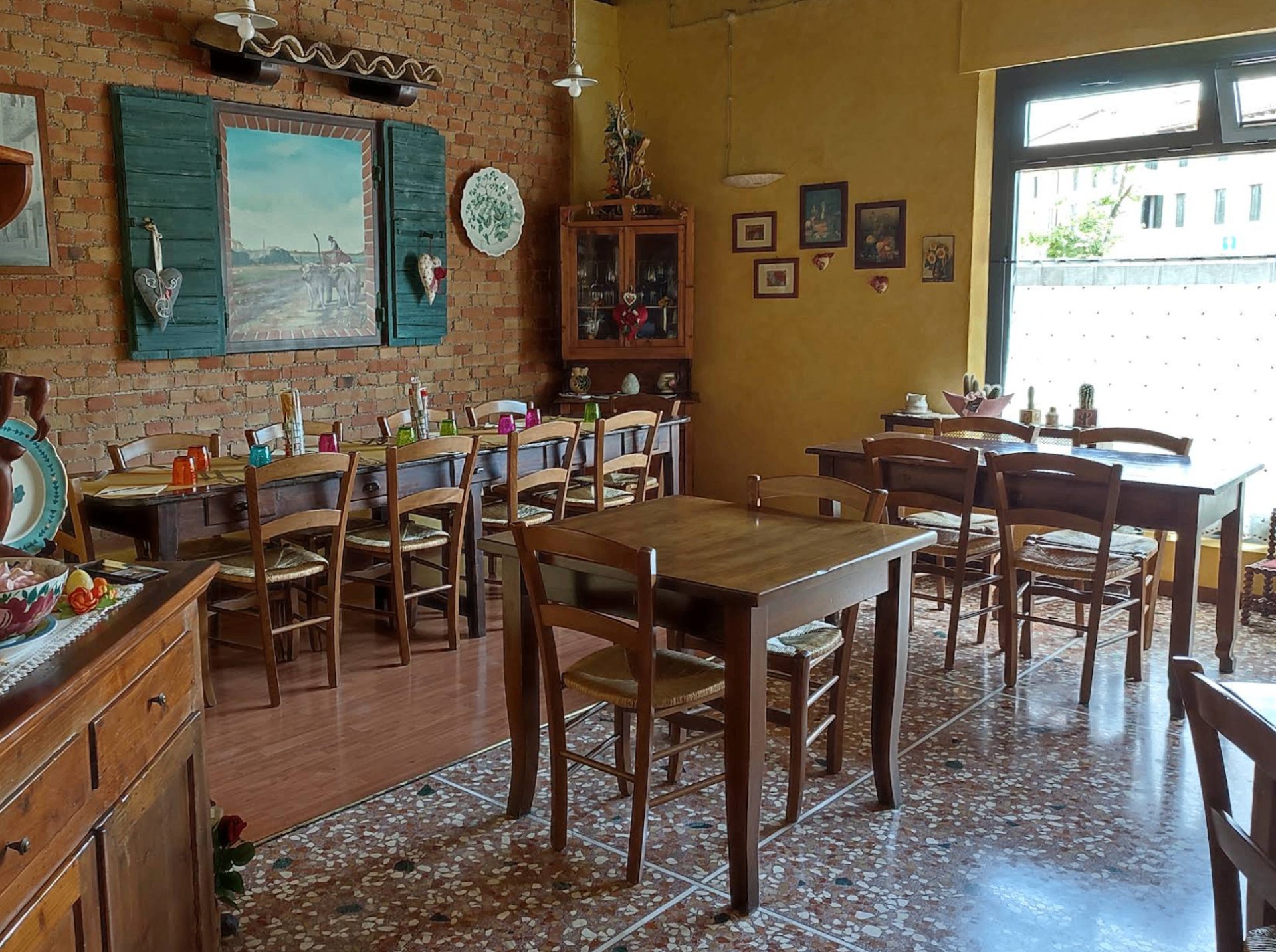 Sala interna del ristorante con tavoli in legno e parete in mattoni